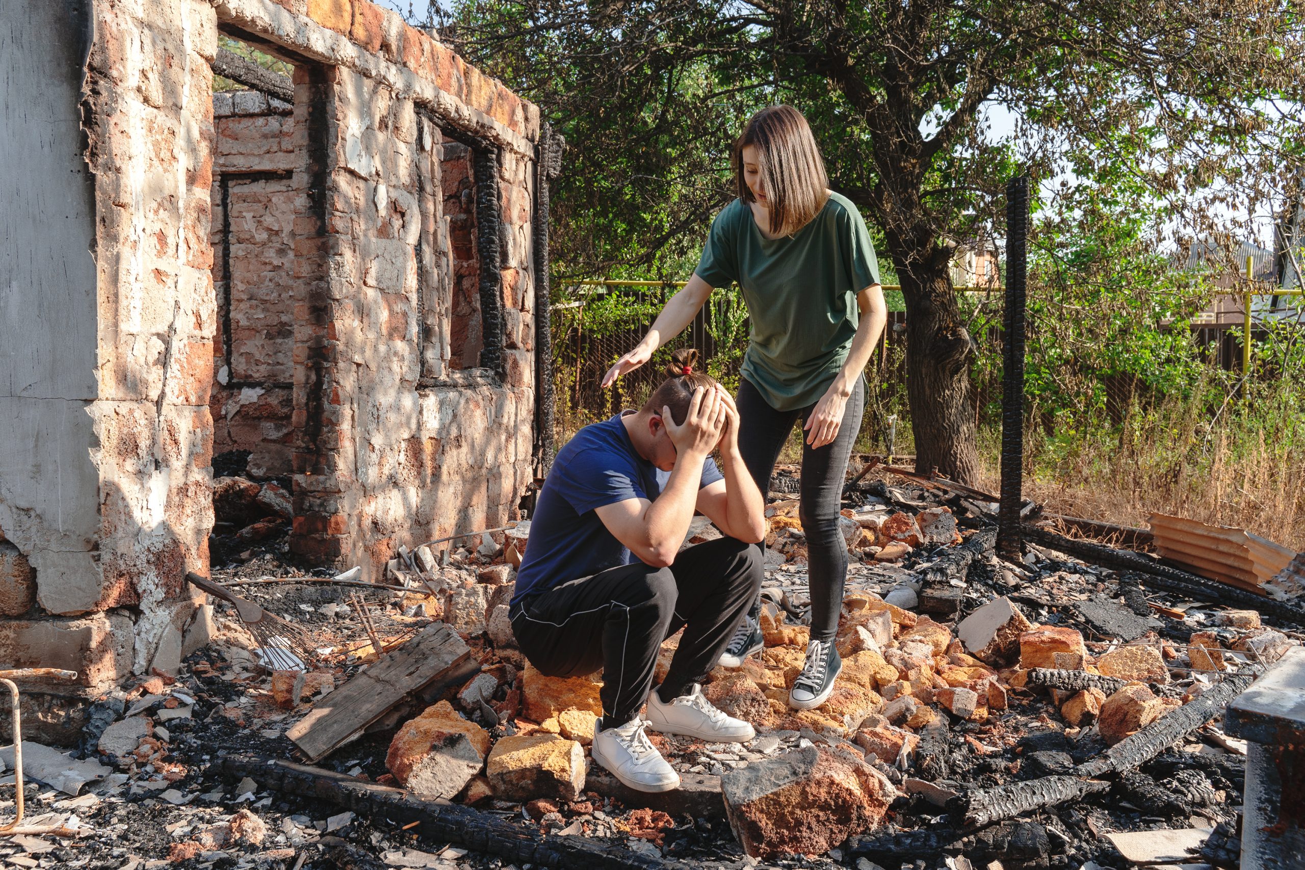 Young couple on the ruins of house destroyed with fire.