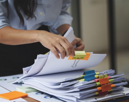 Businesswoman hands working in Stacks of paper files for searching and checking unfinished document achieves on folders papers Businesswoman hands working in Stacks of paper files for searching and checking unfinished document achieves on folders papers